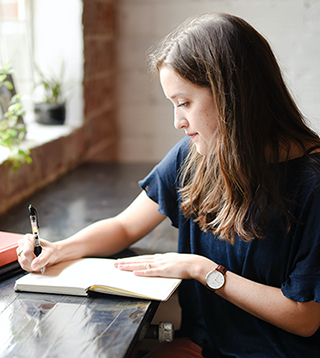 Femme assise à un bureau écrivant dans un carnet