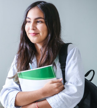 Jeune femme brune qui porte des cahiers de cours et cartable